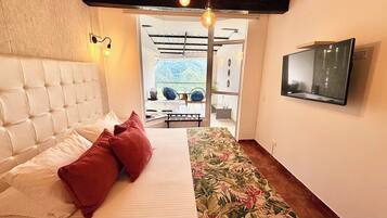 A bedroom with a bed, a TV, and a view of an outdoor area.