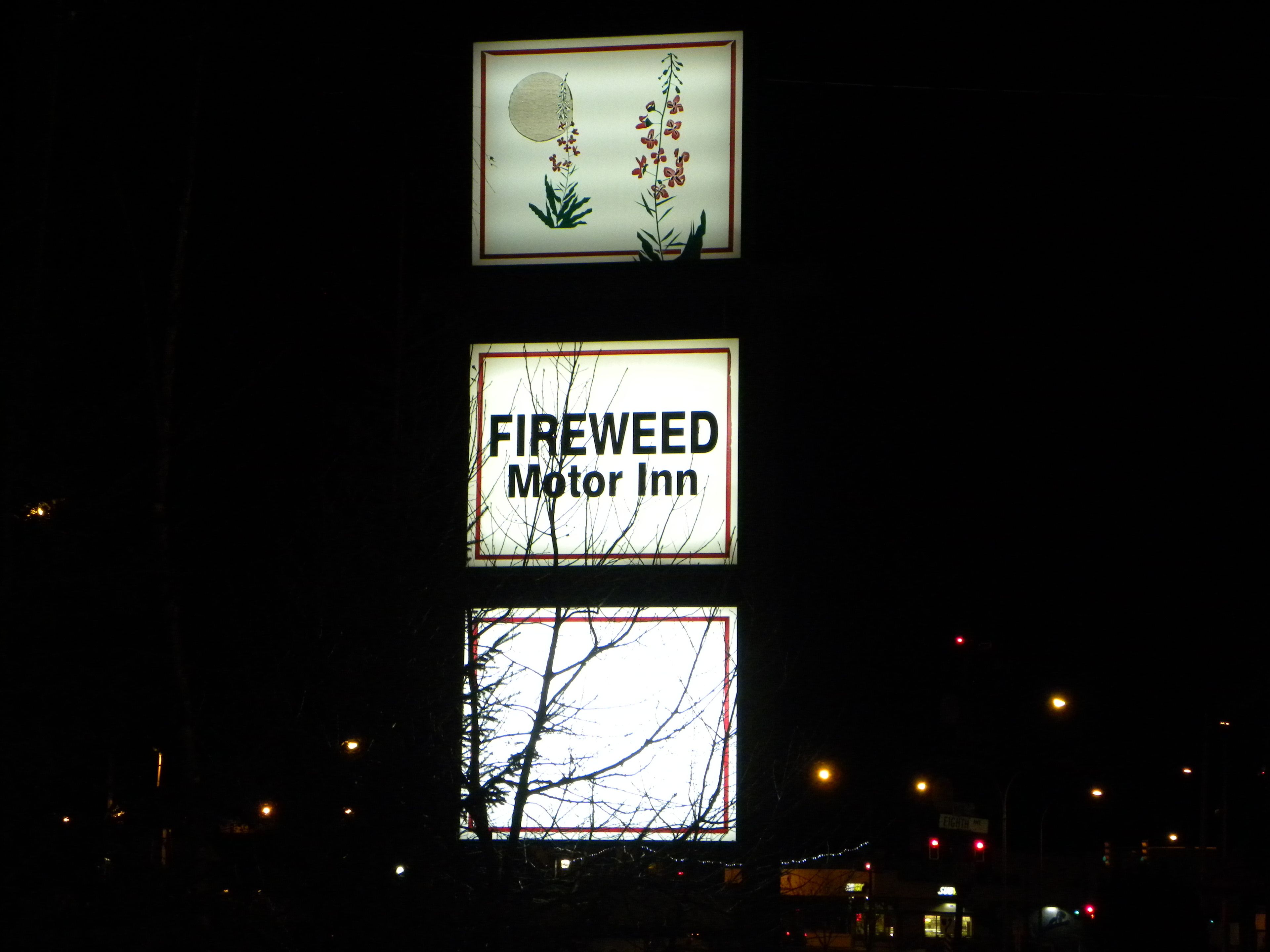 A sign for FIREWEED Motor Inn with a floral design above it.