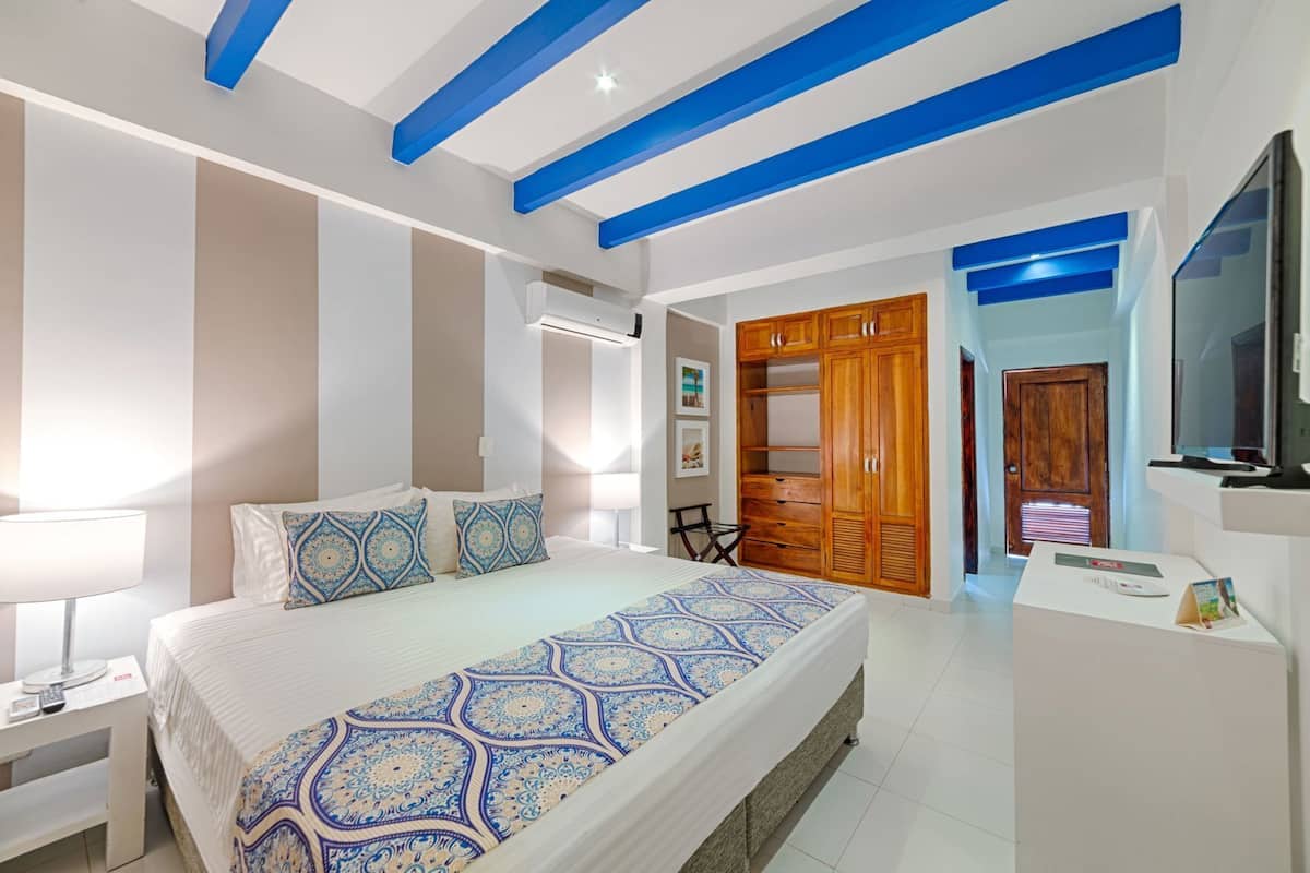 A bedroom with a bed, bedside table, lamp, wardrobe, and a TV.