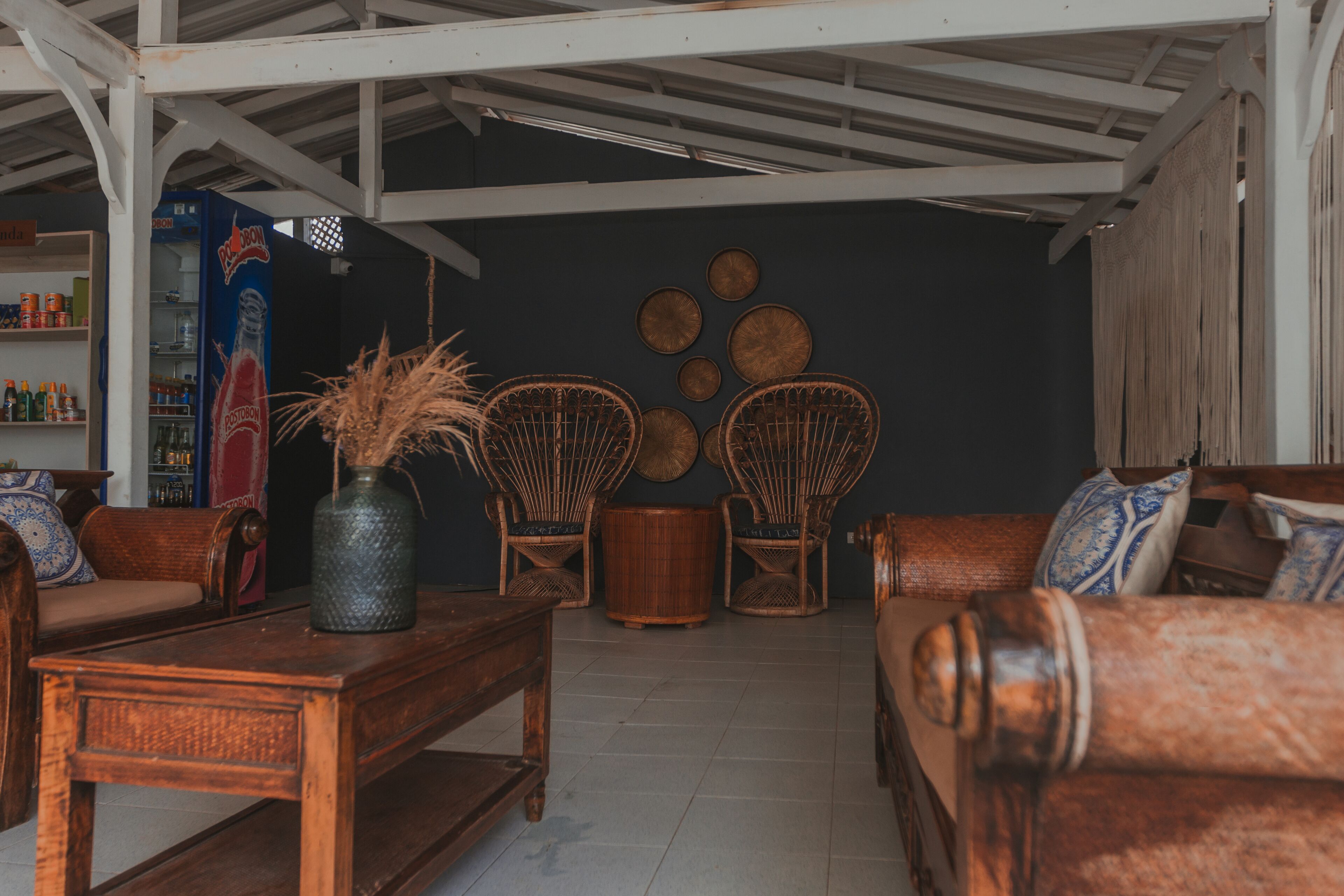 Un rincón acogedor con mobiliario de mimbre, una mesa de estilo vintage y una pared decorativa con diseños circulares.