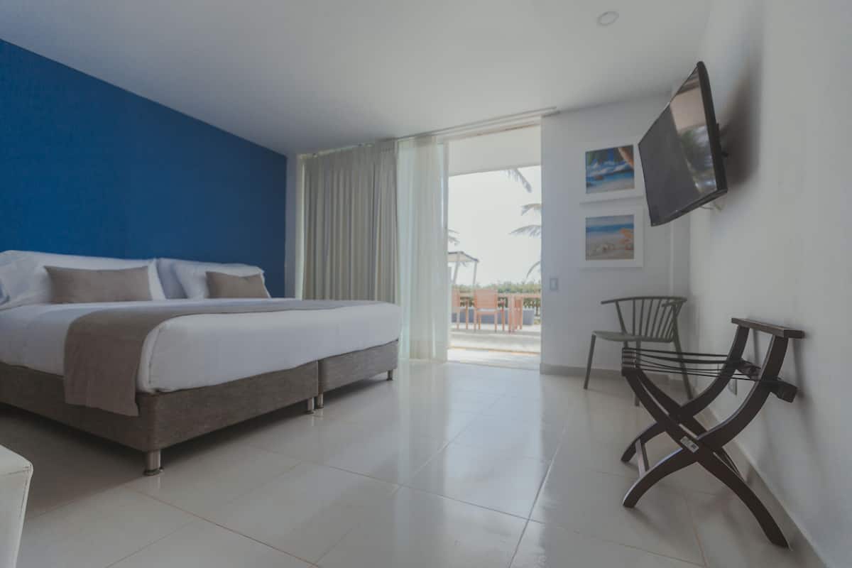 A hotel room with a bed, a TV mounted on the wall, and a balcony with a chair.
