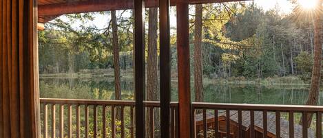 A wooden deck with a view of a forest and a lake.
