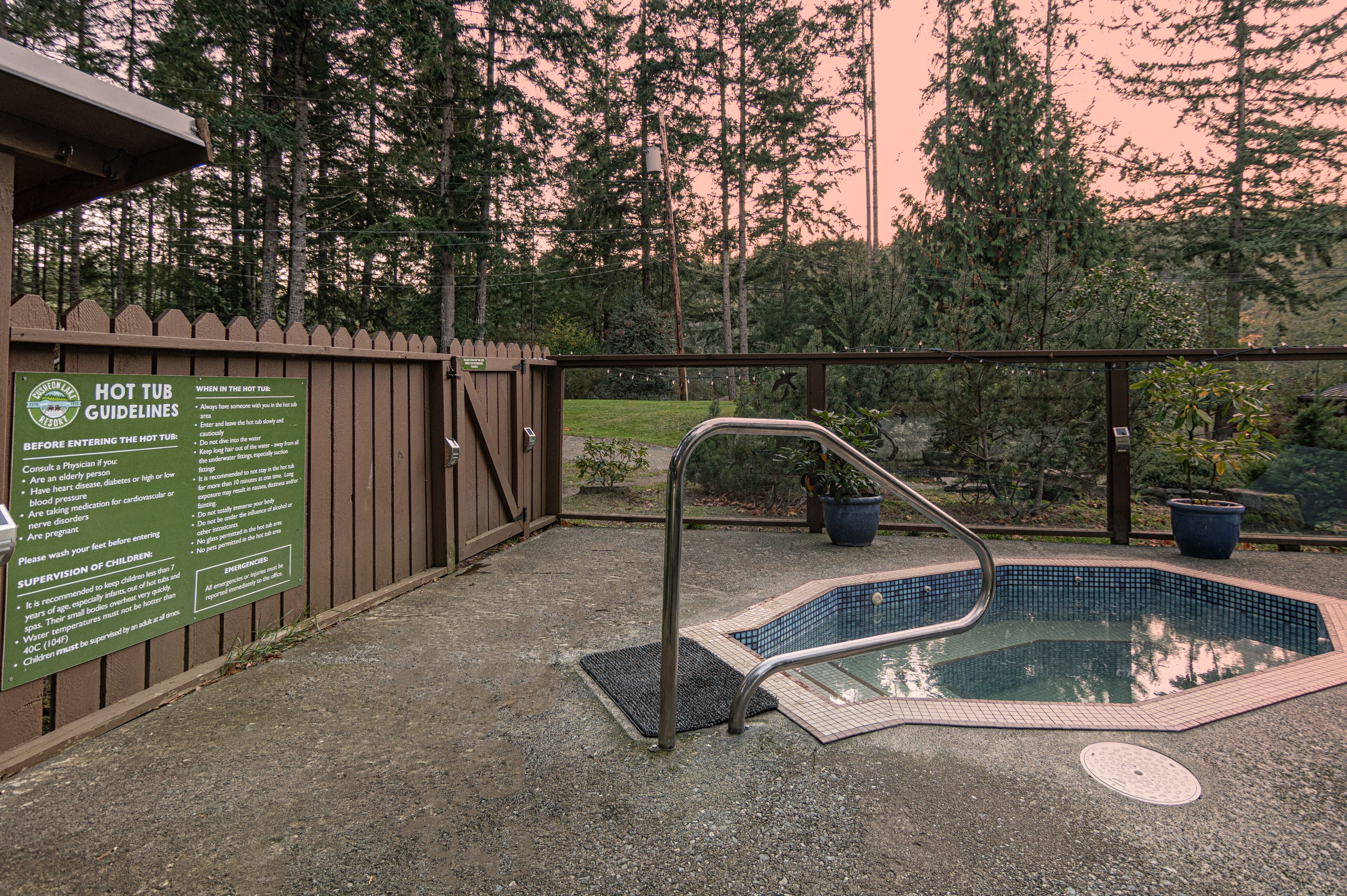 A hot tub with a wooden deck and a sign listing guidelines.