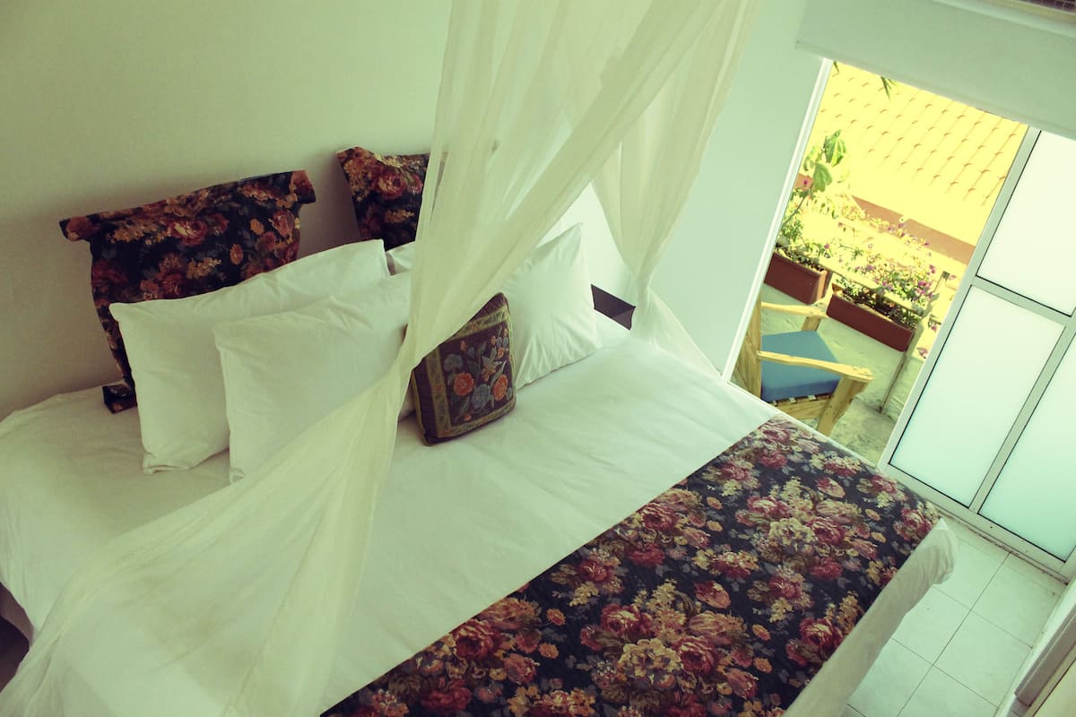 A bed with a floral bedspread, white pillows, and a canopy.