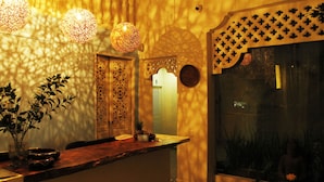 Ambiente accogliente con un bancone in legno, illuminazione decorativa e vista su una statua attraverso una vetrina.
