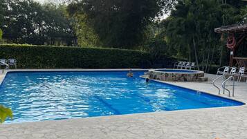 A swimming pool with lounge chairs and a stone-tiled deck.