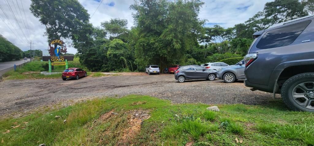 Un cartel de hotel con un restaurante, coches estacionados y una carretera al fondo.