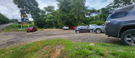 Un cartel de hotel con un restaurante, coches estacionados y una carretera al fondo.