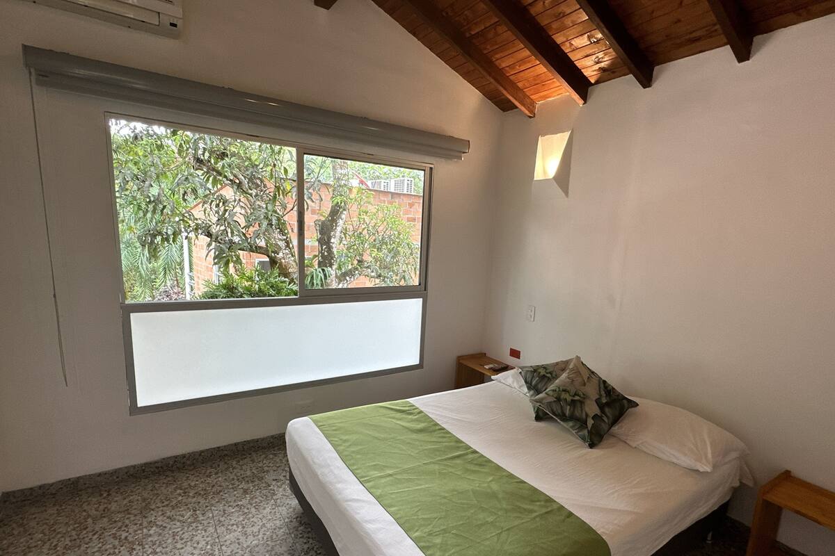 Een slaapkamer met een bed, een raam en een houten plafond.