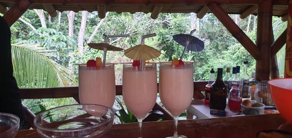 A table with three drinks, a bowl, and various bottles.