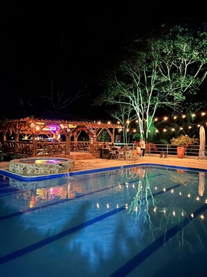 Une piscine extérieure dotée d’une terrasse en bois et d’un espace salon couvert.
