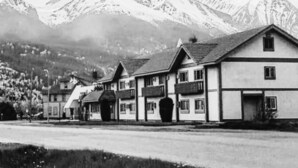 Schwarz-weißes Foto einer Reihe traditioneller Gebäude vor Bergkulisse.