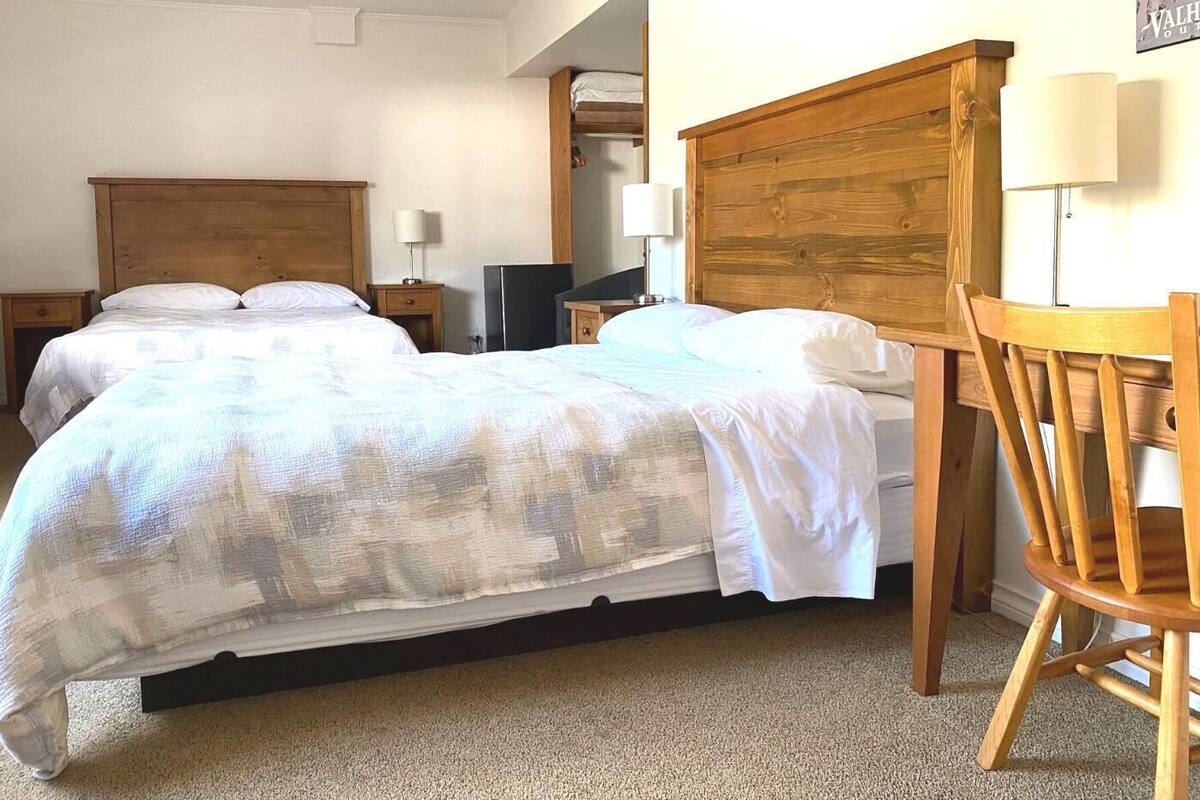 A bedroom with two beds, a wooden headboard, a desk, and a chair.