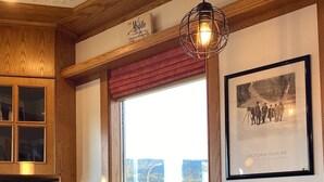Ein Essbereich mit Holztisch und -stühlen, einem gerahmten Foto an der Wand und einem Fenster mit Blick ins Freie.