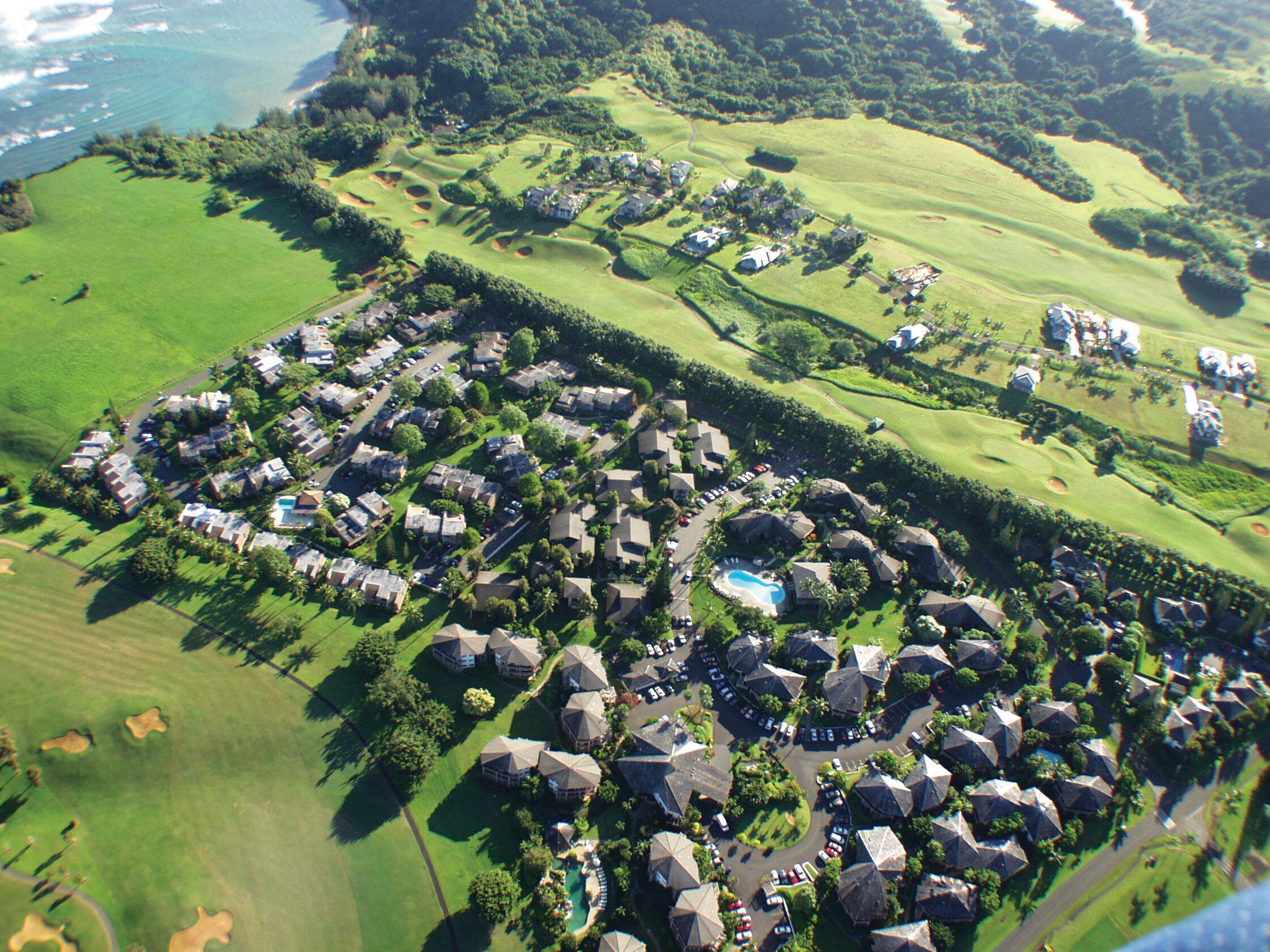 Vista aérea de um campo de golfe com área residencial, incluindo casas e piscina.