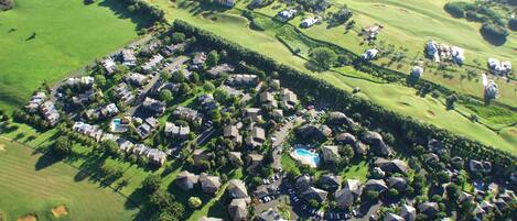 Vista aérea de um campo de golfe com área residencial, incluindo casas e piscina.