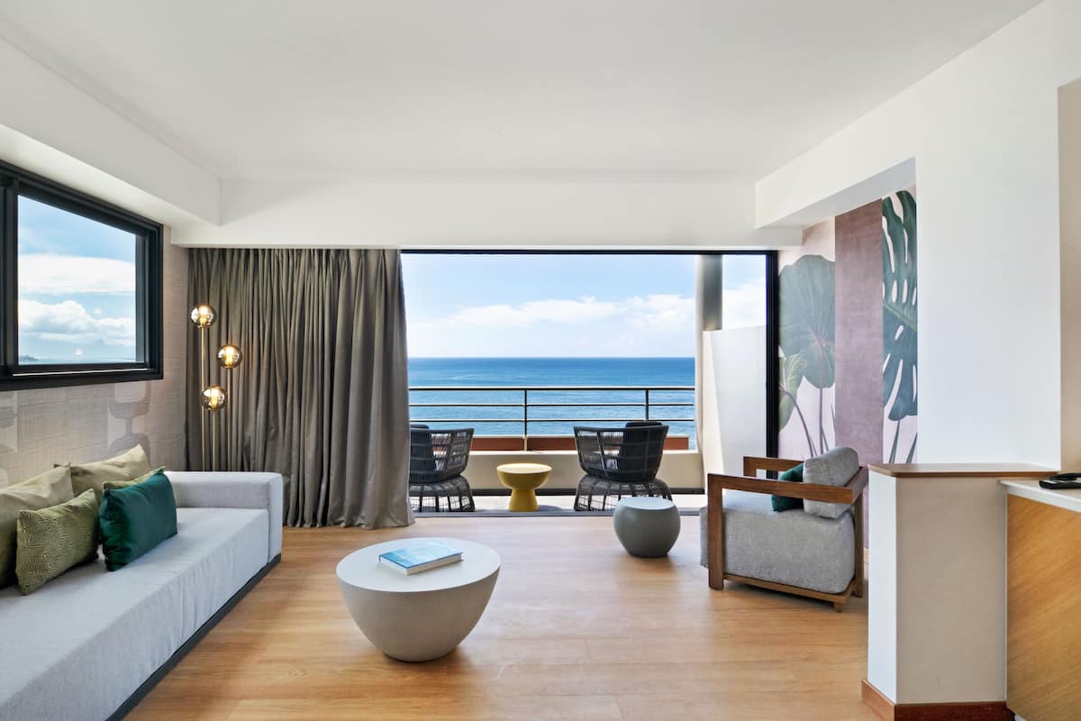Ein modernes Wohnzimmer mit einer Couch, einem runden Couchtisch und Blick auf den Ozean.