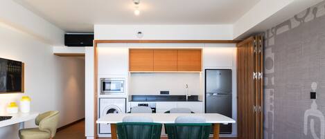A modern kitchen with white cabinets, a built-in oven, and a stainless steel refrigerator.