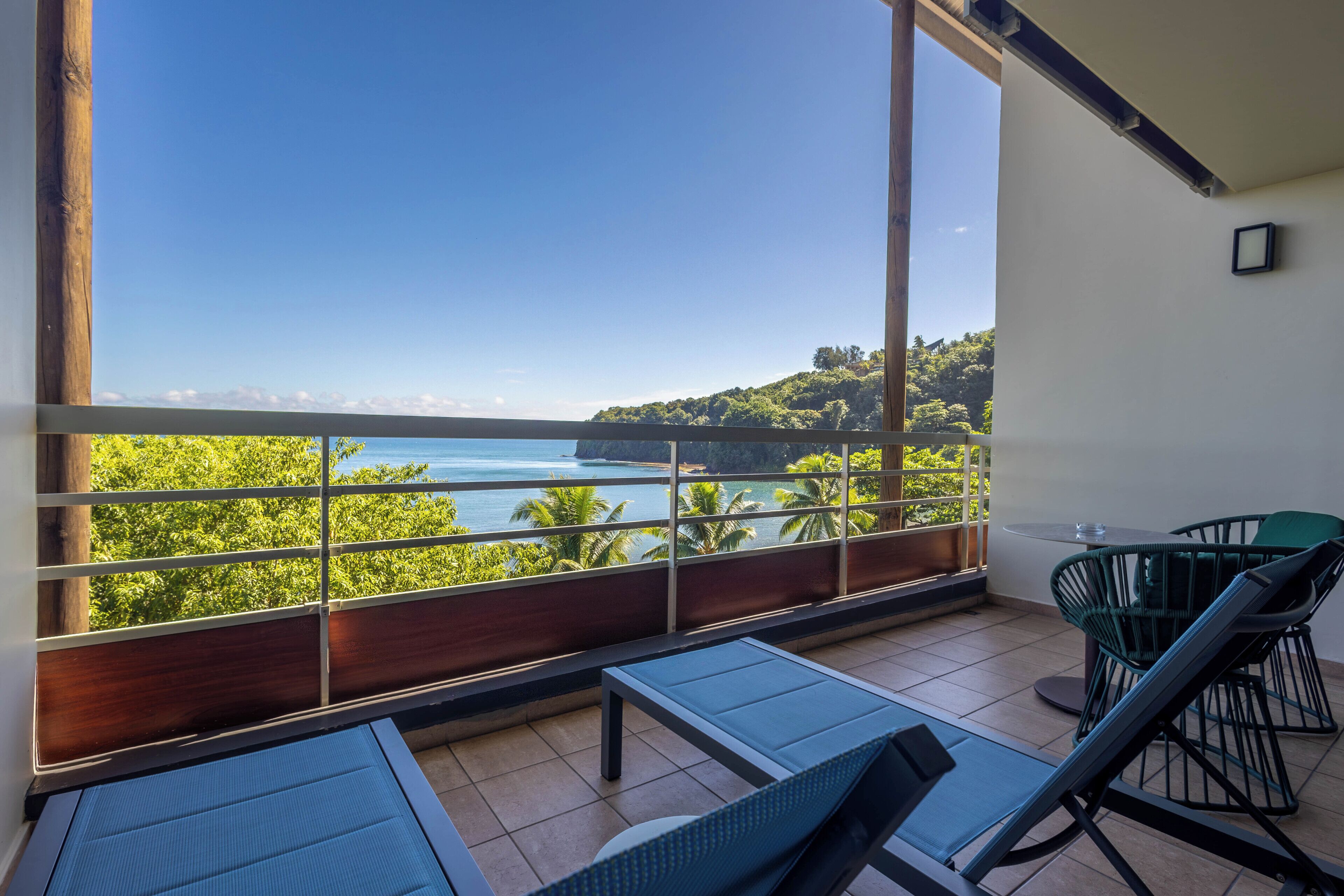 A balcony with a view of the sea, a table, and two chairs.