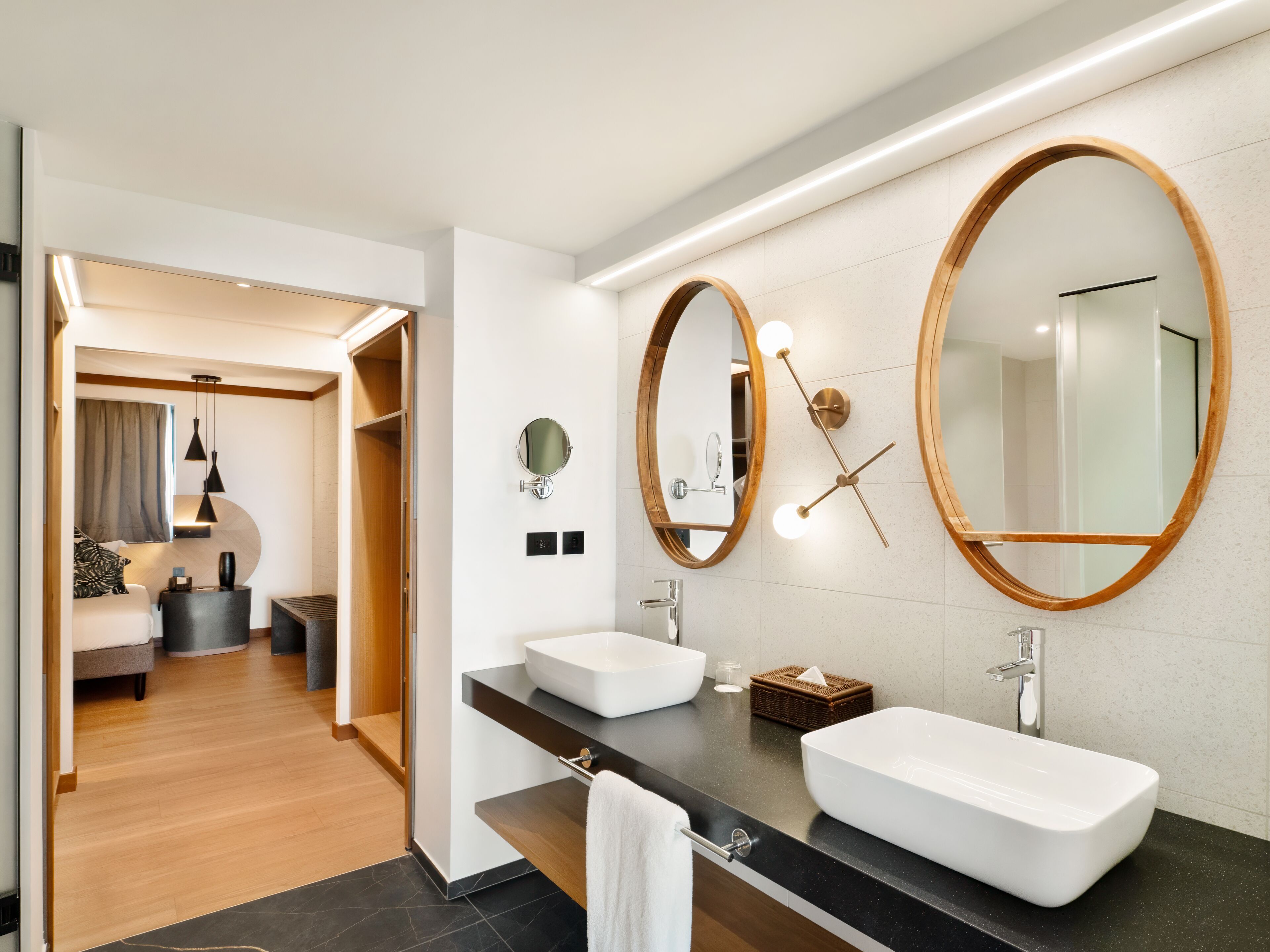 A modern bathroom with two sinks, a large mirror, and a wooden-framed mirror.