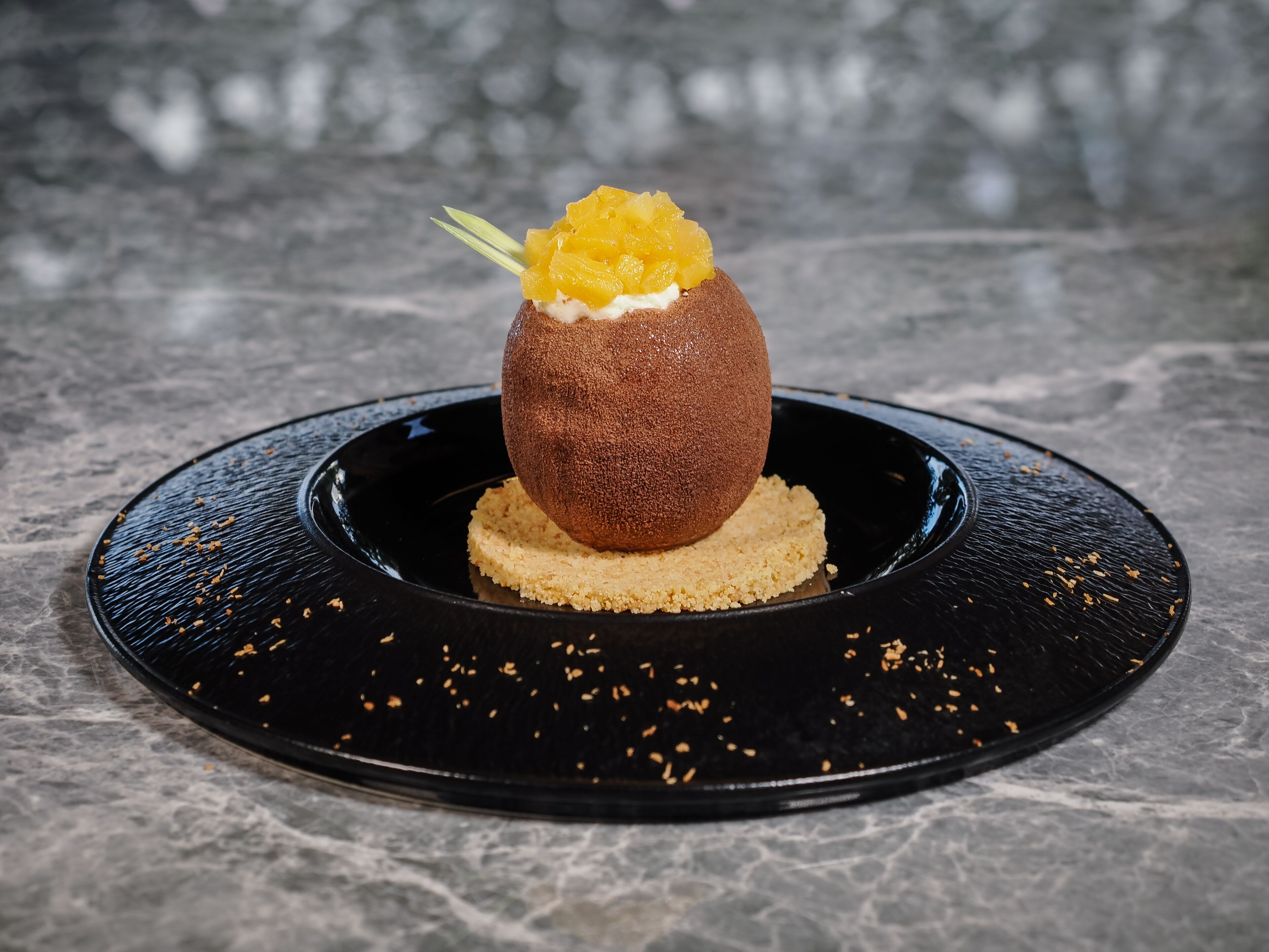 A dessert on a black plate with a textured base.