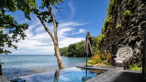 A private pool with a clear view of the sea, surrounded by a rocky cliff and lush greenery. - Tahiti Pearl Beach Resort (Arue)