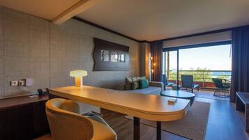 Habitación de hotel moderna con una larga mesa de comedor, un sofá, una silla, una lámpara y vistas al exterior.