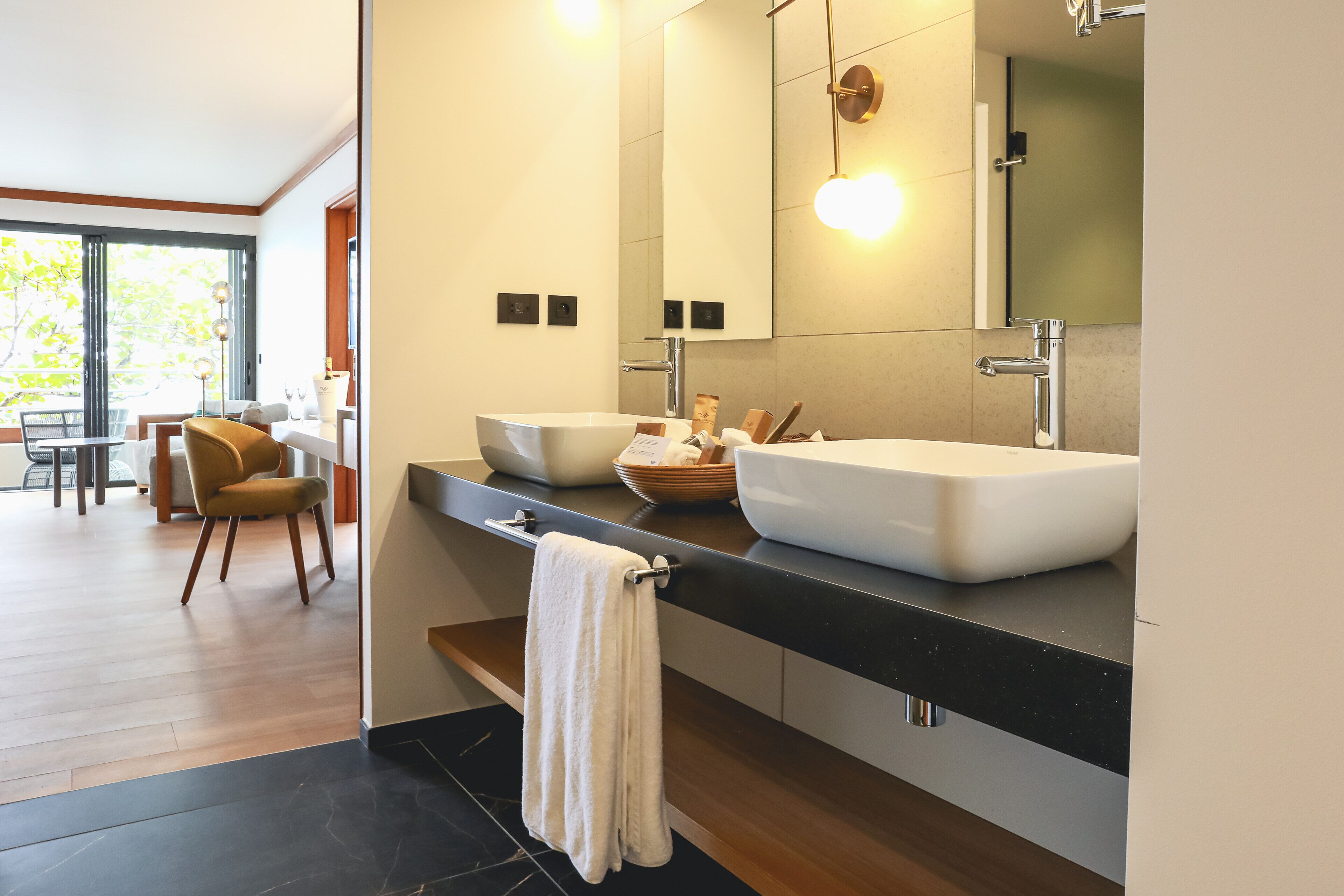 Un baño moderno con un espejo grande, dos lavamanos y un perchero para toallas.