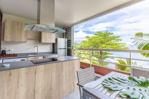 A modern kitchen with a large island, a built-in oven, and a window overlooking a lush landscape.