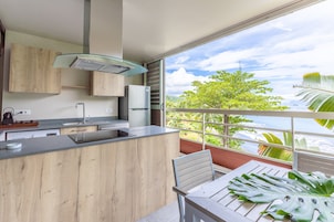 A modern kitchen with a large island, a built-in oven, and a window overlooking a lush landscape.