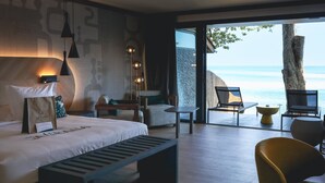 A modern hotel room with a large bed, a bench, a desk, and a view of the sea. - Tahiti Pearl Beach Resort (Arue)