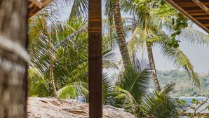 A wooden structure with a thatched roof overlooking a beach with palm trees and a view of the sea. - Amami Beach Resort (Puerto Galera)