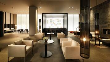 A modern lounge area with sofas, tables, and a large display wall.
