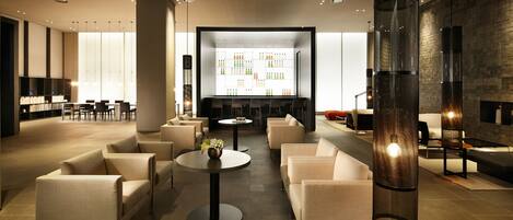 A modern lounge area with sofas, tables, and a large display wall.
