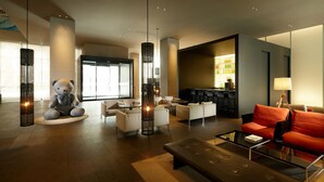 A modern lobby with a large bear sculpture, seating areas, and a bar. - Shilla Stay Jeju Airport (Jeju City)