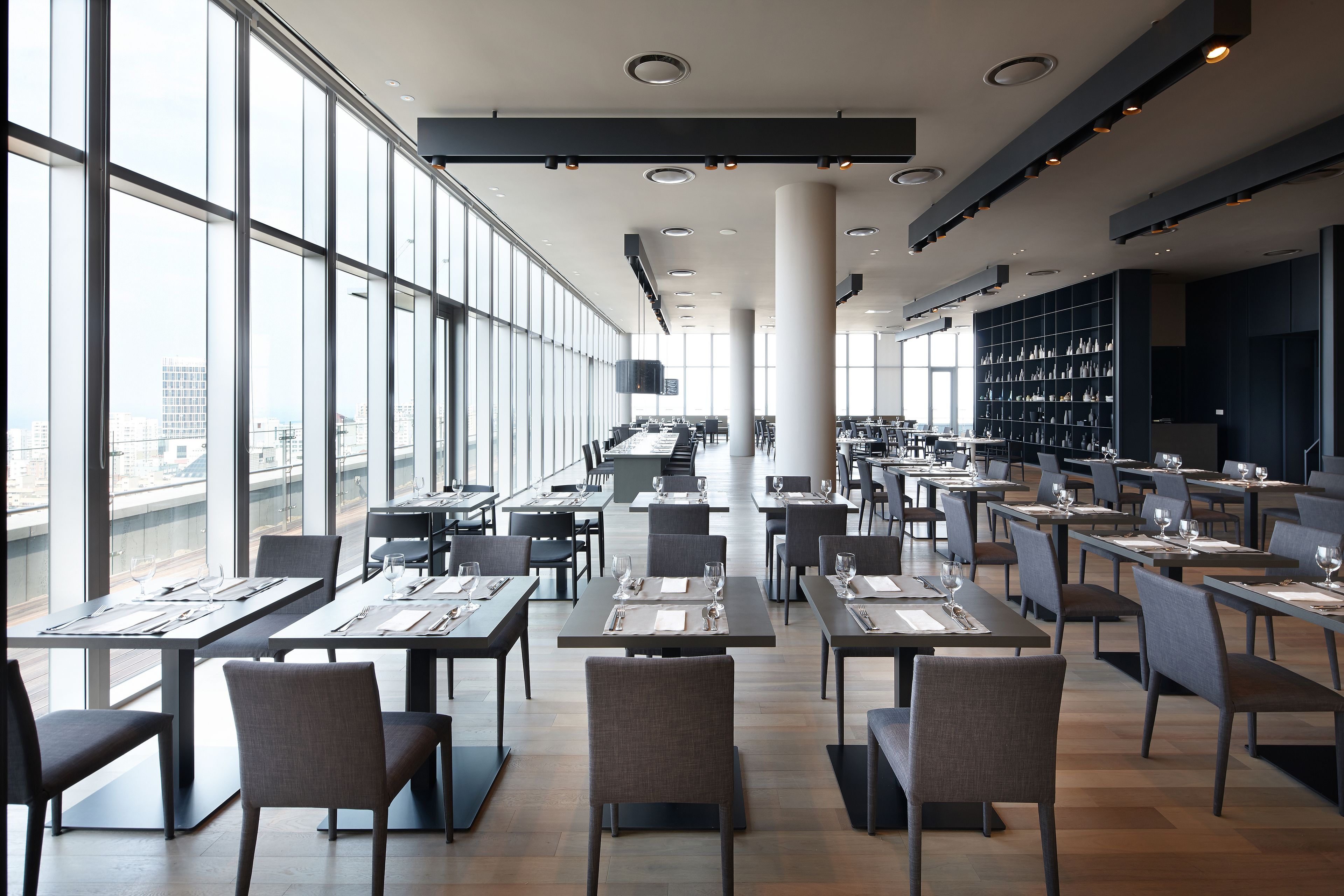 Un espace de restauration moderne, doté de tables et de chaises, de grandes fenêtres et offrant une vue sur la ville.
