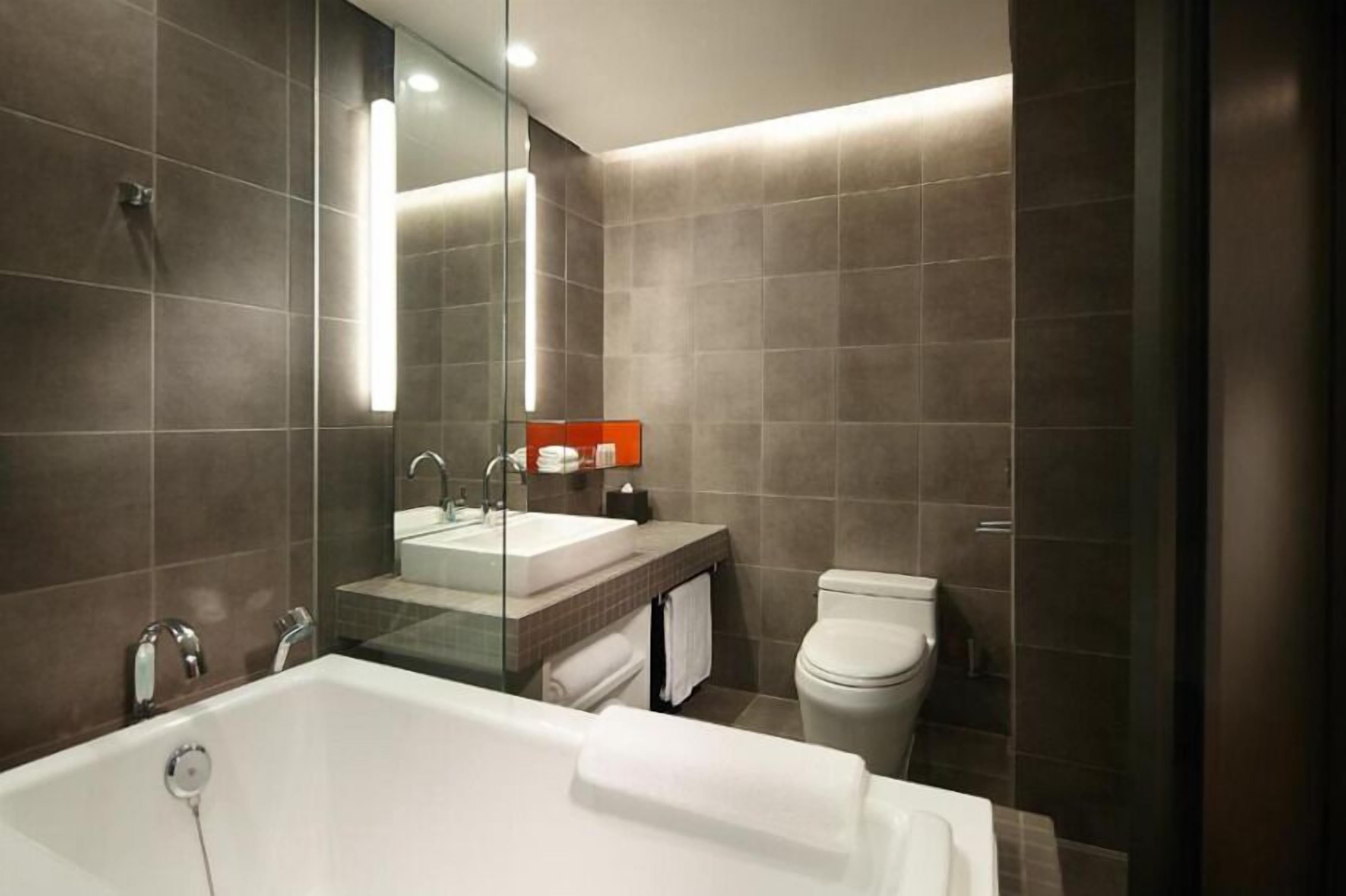 A modern bathroom with a large bathtub, a double sink vanity, and a toilet.