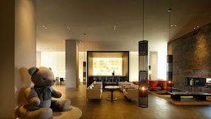 A modern lobby with a large bear sculpture, seating area, and a fireplace. - Shilla Stay Jeju Airport (Jeju City)