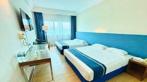 A hotel room with two beds, a desk with a lamp, a TV, and a window with curtains. - Tyng Garden Hotel (Sandakan)