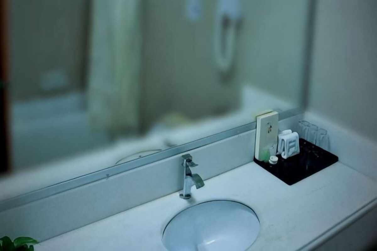 A bathroom with a sink, mirror, and a small black tray with toiletries.