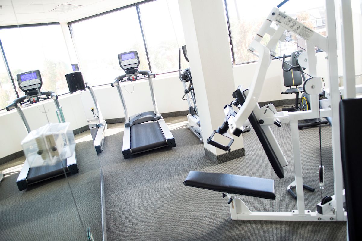 Ein Fitnessstudio mit Laufbändern, Crosstrainern und Gewichten.