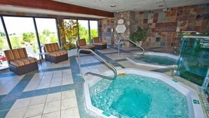 Un área de spa con dos jacuzzis, asientos y una pared de piedra.