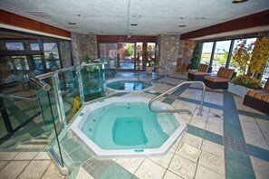 A spa area with two hot tubs, glass railings, and a seating area with a view of the outside. - Carson Valley Motor Lodge & Suites (Minden)