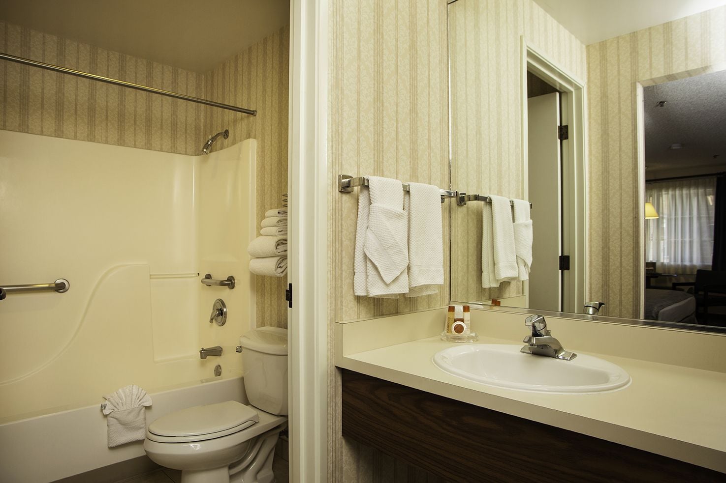 A bathroom with a bathtub, toilet, and sink. There are towels hanging on a rack.