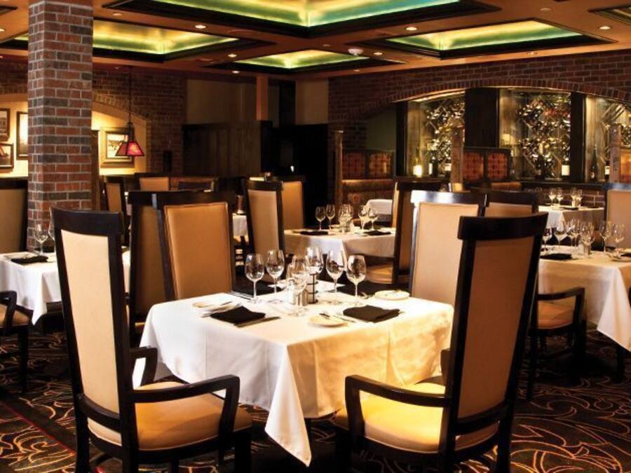 A restaurant with multiple tables set for dining, featuring a brick wall and framed artwork on the walls.