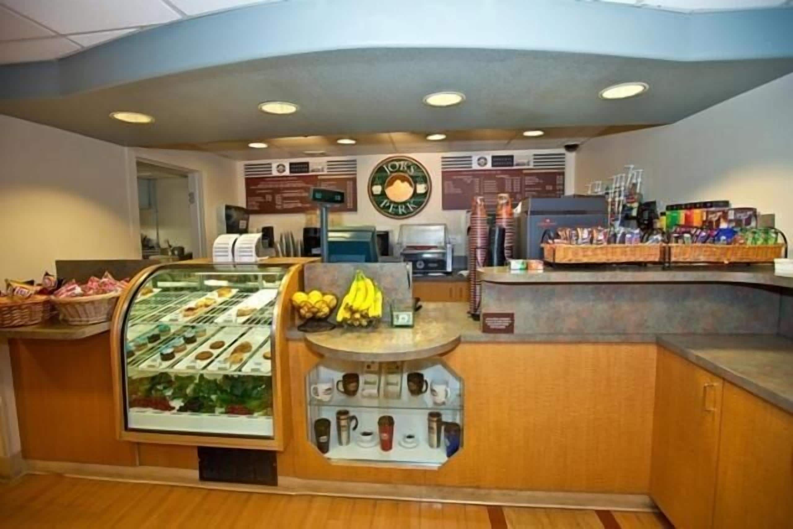 A breakfast counter with a display case of pastries, a fruit display, and a coffee station.