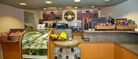 A breakfast counter with a display case of pastries, a fruit display, and a coffee station.