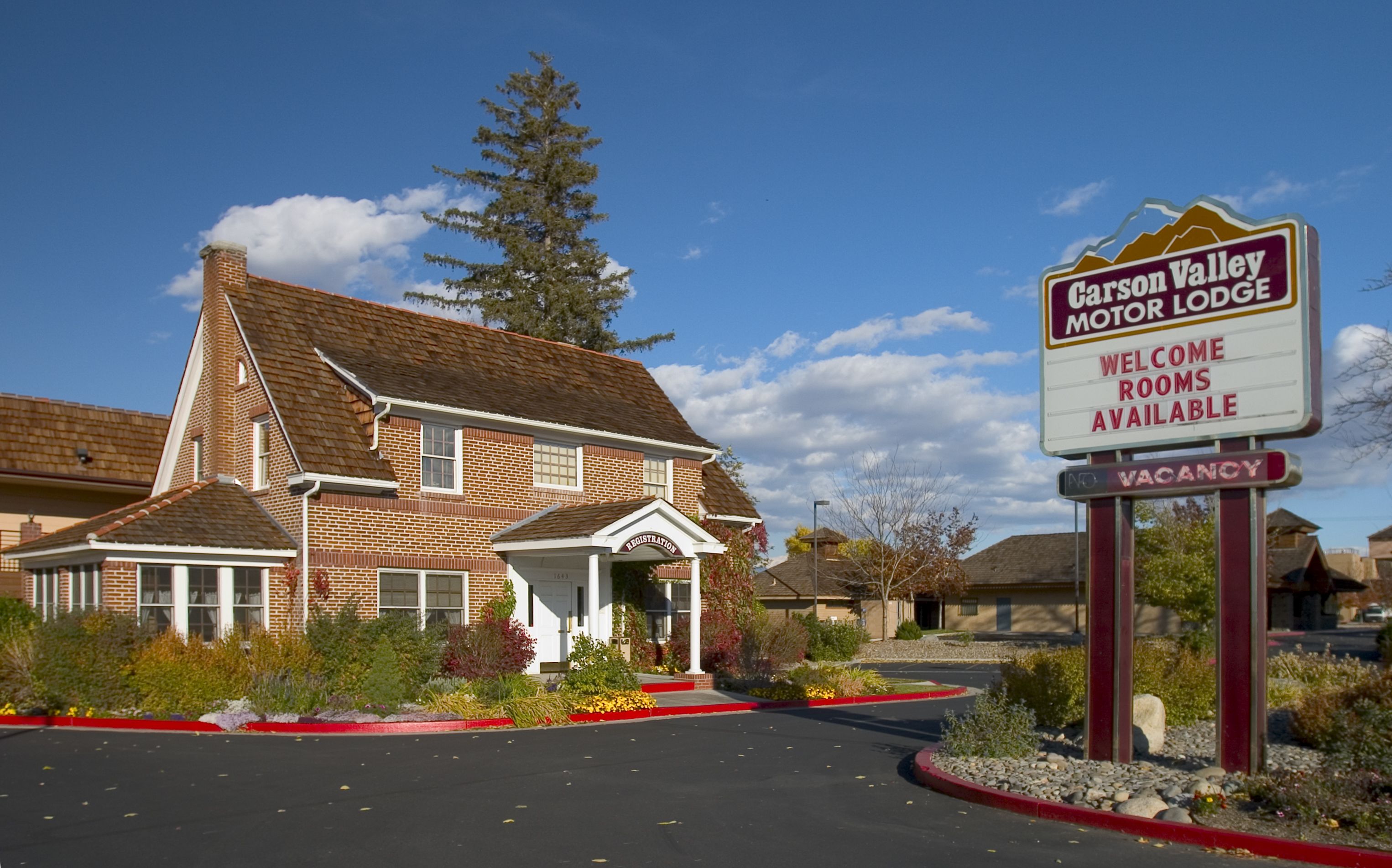 Un bâtiment en briques avec une enseigne indiquant « Carson Valley Motor Lodge » et précisant que des chambres sont disponibles.