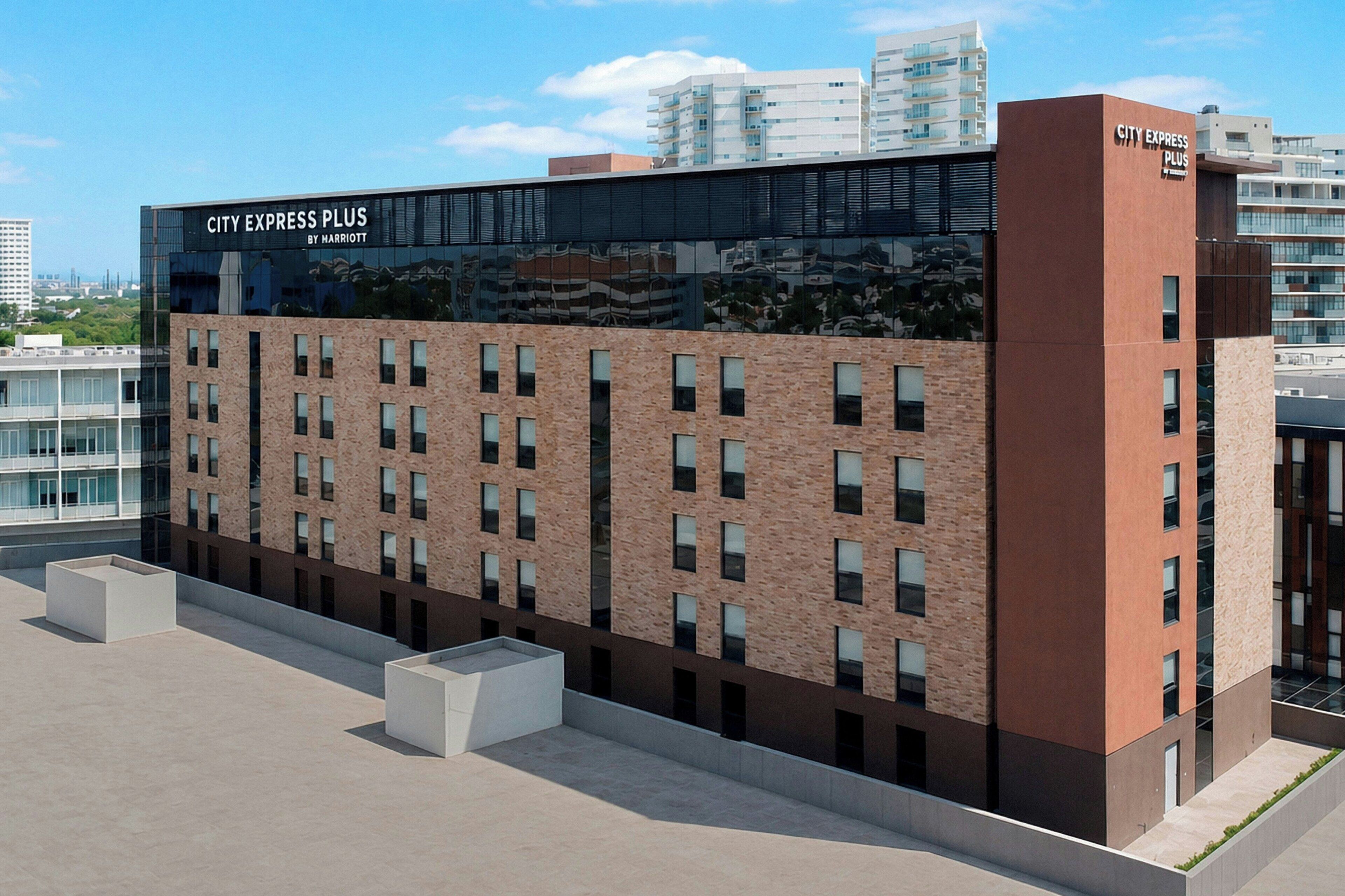 A modern hotel building with a brick facade, large windows, and a rooftop area.