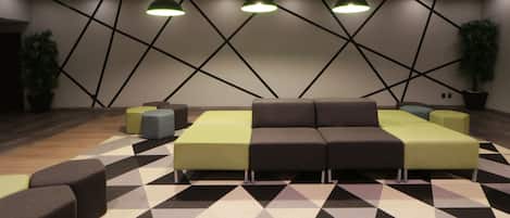 A modern lounge area with geometric patterned flooring, a sectional sofa, and pendant lighting.